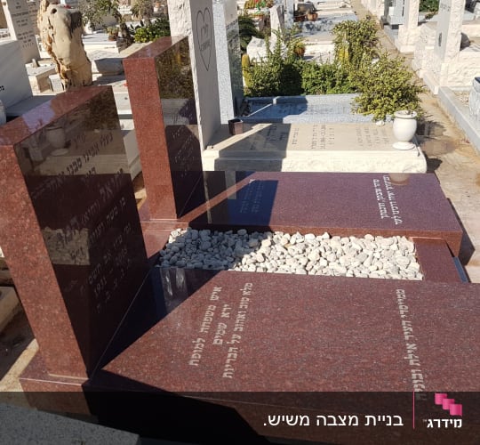 מצבה כפולה מגרניט אדום מלוטש עם חלוקי נחל לבנים בבית עלמין